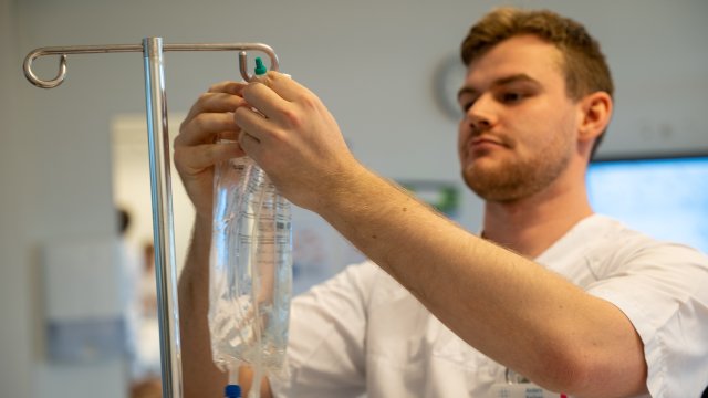 Mann henger opp væskepose på et stativ