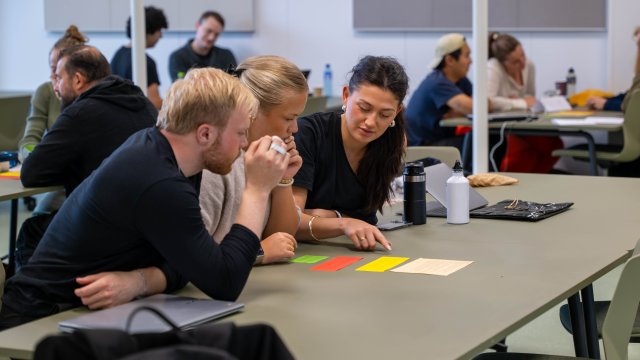 Tre studenter diskuterer en oppgave