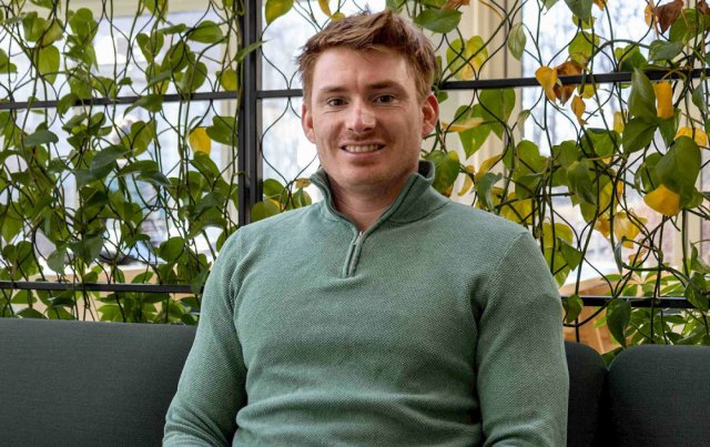 Ung mann sitter foran en begg med planter