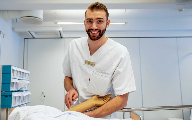 Mannlig sykepleier øver på en dukke