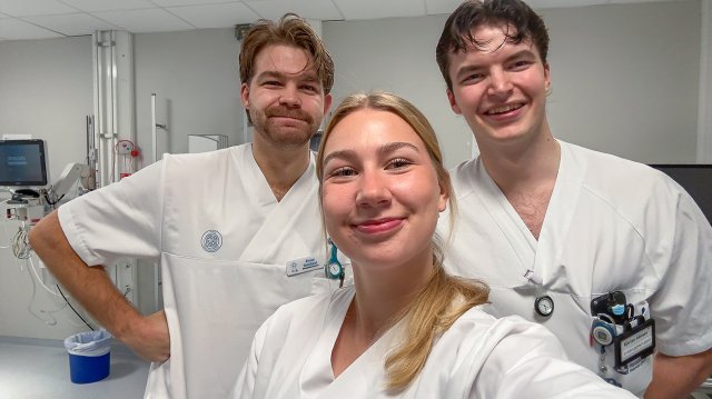 Tre sykepleierstudenter som smiler og ser i kamera