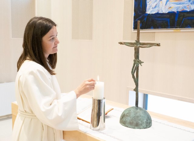 Prest tenner et lys ved et alter