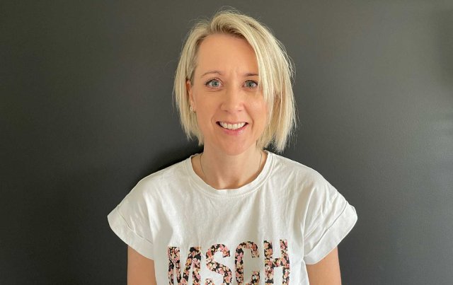 Ung dame med blondt hår se i kamer aog smiler