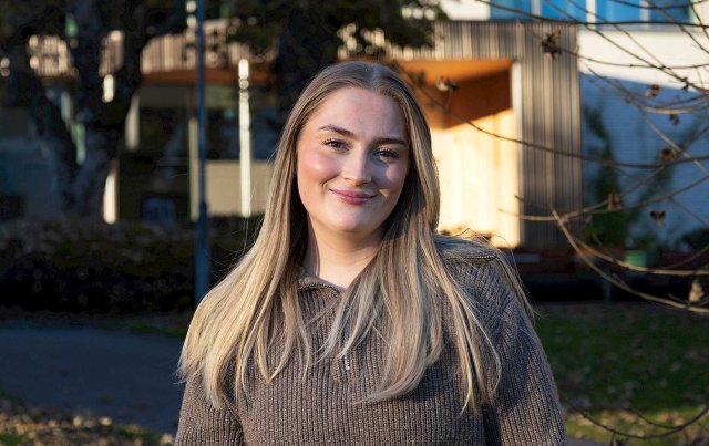 Jente med langt lyst hår ser i kamera og smiler.