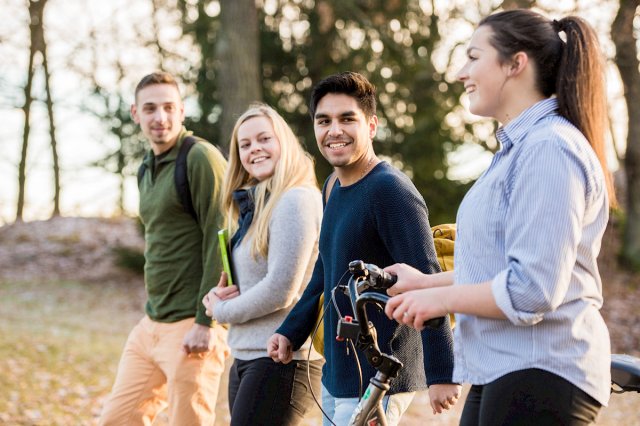 Fire studenter i en allé i høstsolen